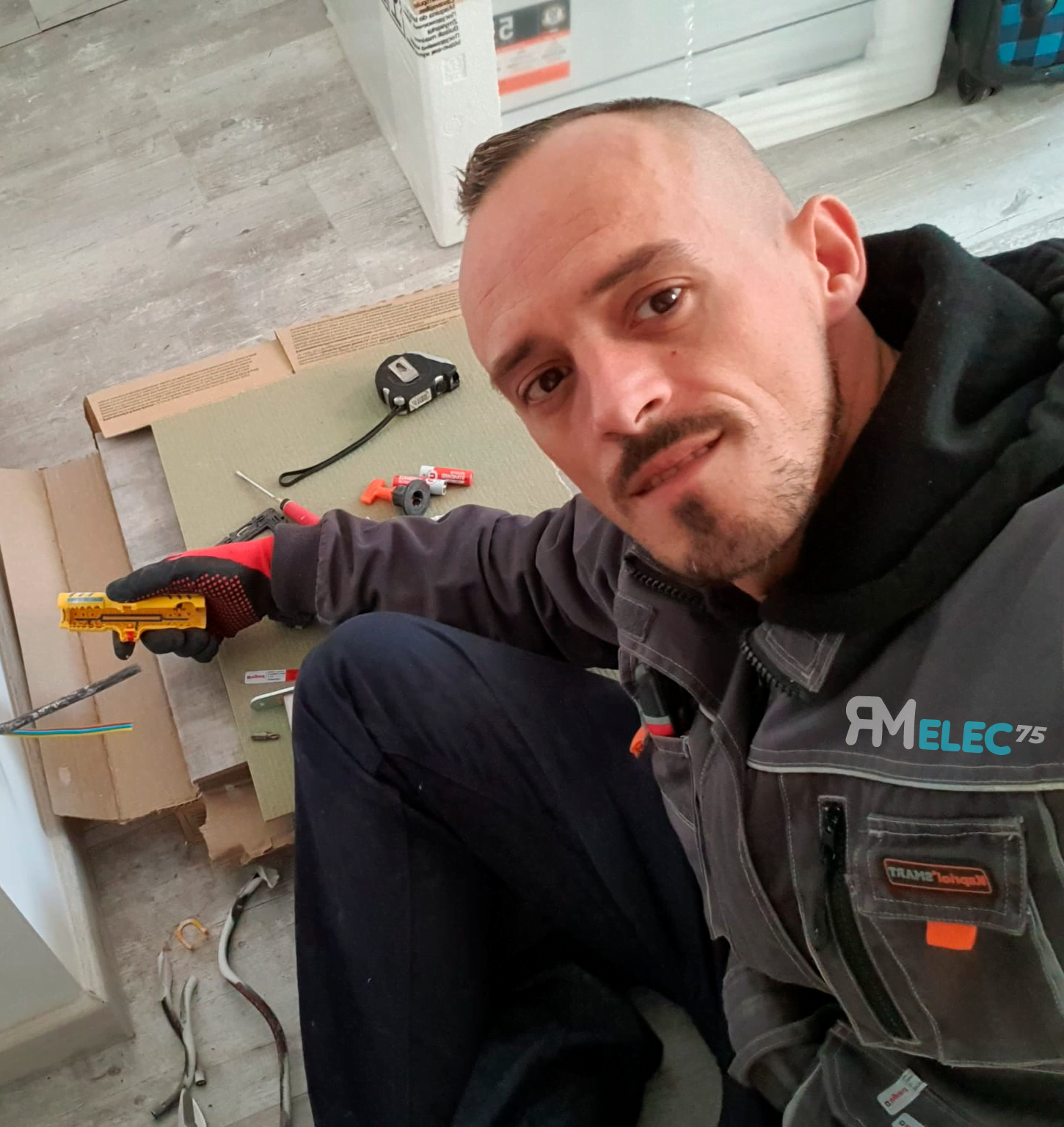 Électricien travaillant avec un testeur de tension jaune sur des câbles électriques dans un mur.
